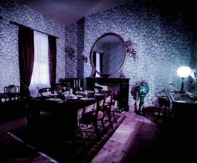 The inside of Black Rock House, one of the most haunted houses in Melbourne. This appears to be a dining room, with patterned wallpaper, a dining table and chairs, decorated in an old-fashioned manner