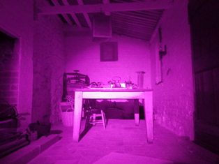 The inside of Black Rock House shows an eerie purple colour. There is a desk in a small room. 