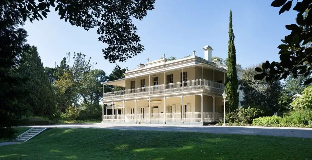 The exterior of Como House shows a large mansion painted cream and white, set back from lush green grass. Como House is one of the most haunted houses in Melbourne, with several ghostly stories.
