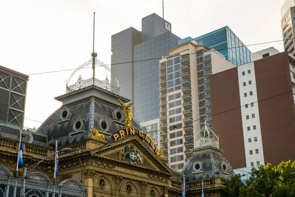 The. Princess Theatre is one of the most haunted places in Melbourne - this image shows the Princess Theatre's golden logo at the top of the building, surrounded by modern skyscrapers in Melbourne